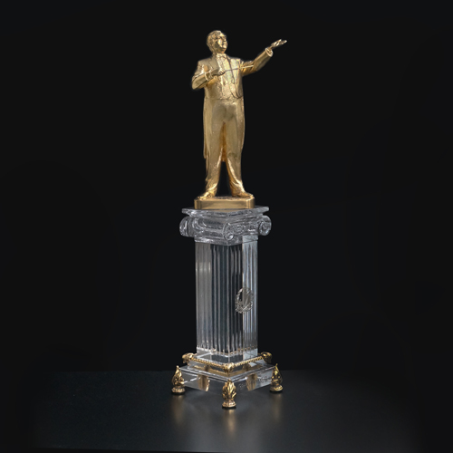 приз  из позолоченной бронзы скульптура  дирижера с портретным сходством на  колонне подиуме с капителью изготовленной из классического  хрусталя 